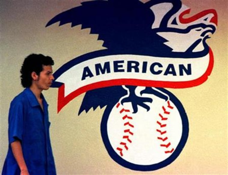 An employee of the Rawling baseball factory walks in front of the logo of the American League
