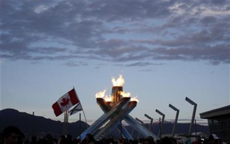 A Canadian flag is seen in front of the Olympic cauldron during celebrations for Canada's victory over the US in the men's ice hockey gold medal game at the Vancouver 2010 Winter Olympics