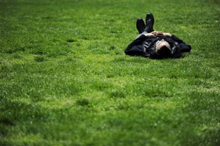 A man takes a break on a sunny day on the grass of LaFayette Park near the White House in Washington