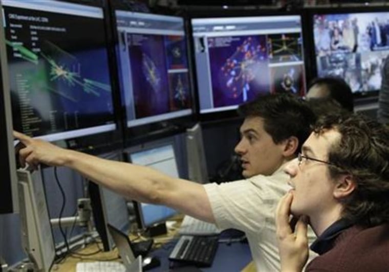 Scientists look at pictures of the first successful collisions at full power at the CMS experience control room of the LHC at the CERN in Meyrin
