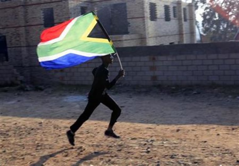 A worker runs with the South African flag inside the Soccer City stadium in Soweto