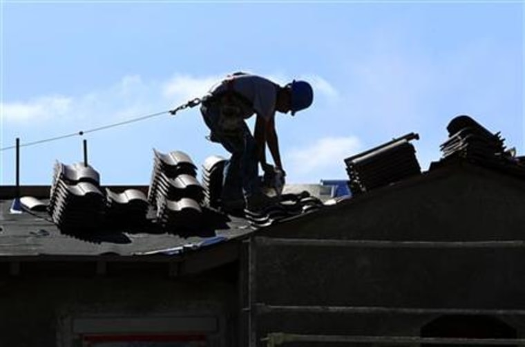A construction worker cuts tiles as he installs a roof on a home in a new subdivision being built in San Marcos, California