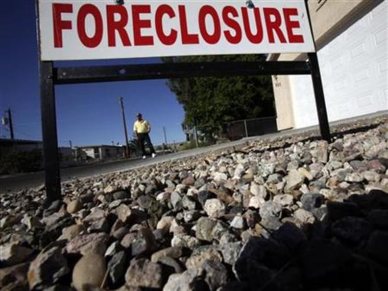 Realtor Mac McCollum stands in front of a foreclosed home in Bullhead City, Arizona