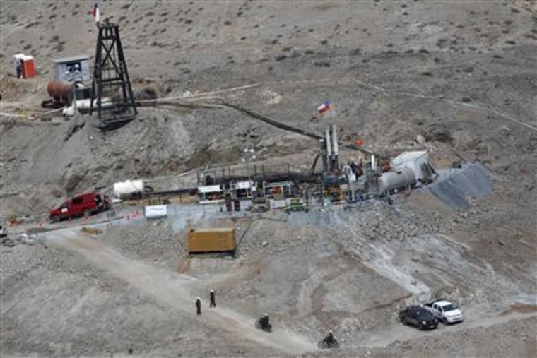Workers operate the Xtrata 950 drill, which is digging a hole for trapped miners to escape from, in Copiapo
