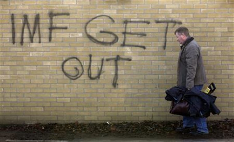 A man carrying his tools walks near a graffiti in South Dublin