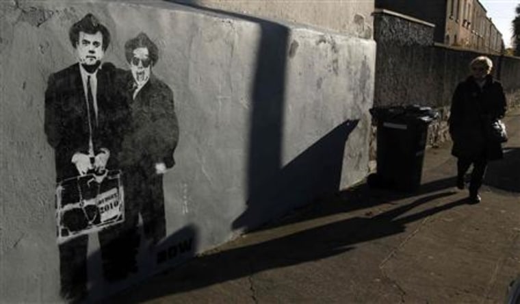 A woman walks past graffiti depicting Ireland's Finance Minister Brian Lenihan and Prime Minister Brian Cowen as the Blues Brothers Dublin
