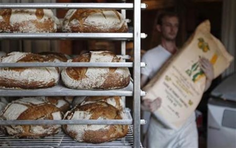 A French baker carries a bag of flour near freshly-baked traditional bread in Strasbourg