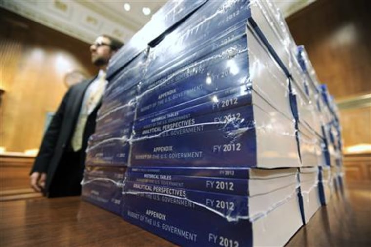 Staff members wait to hand out stacks of Obama's proposed 2012 federal budget in Washington