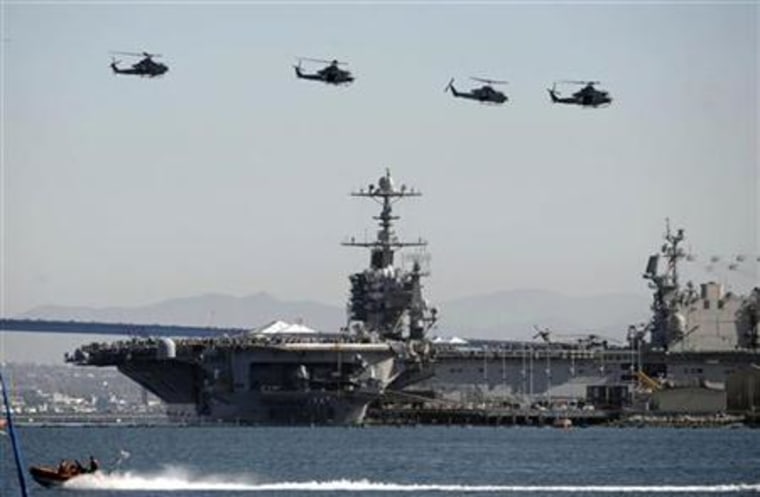 Crowds aboard the aircraft carrier USS John C. Stennis watch as U.S. Navy helicopters fly past the ship in San Diego
