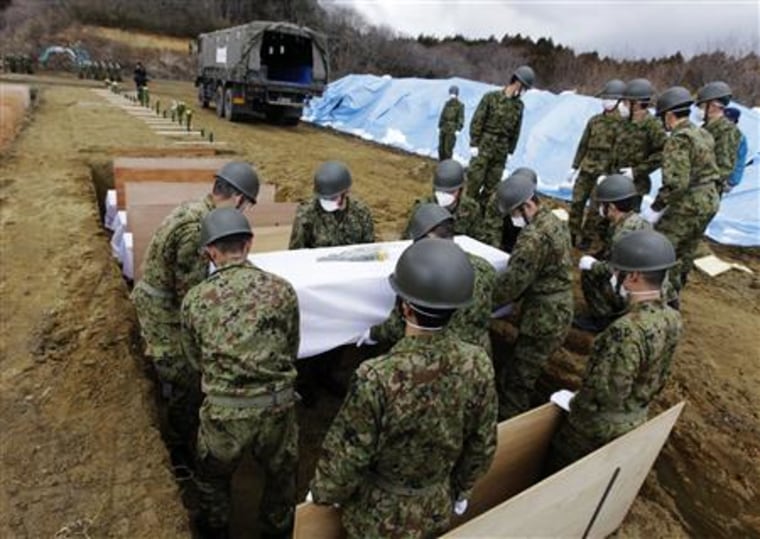 Members of the Japan Ground Self Defense Force carry the coffin of a victim of the tsunami at a temporary mass grave site in Higashi Matsushima