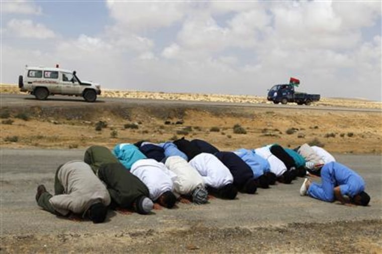 Medical staff pray along the road to Brega, as they wait for wounded people