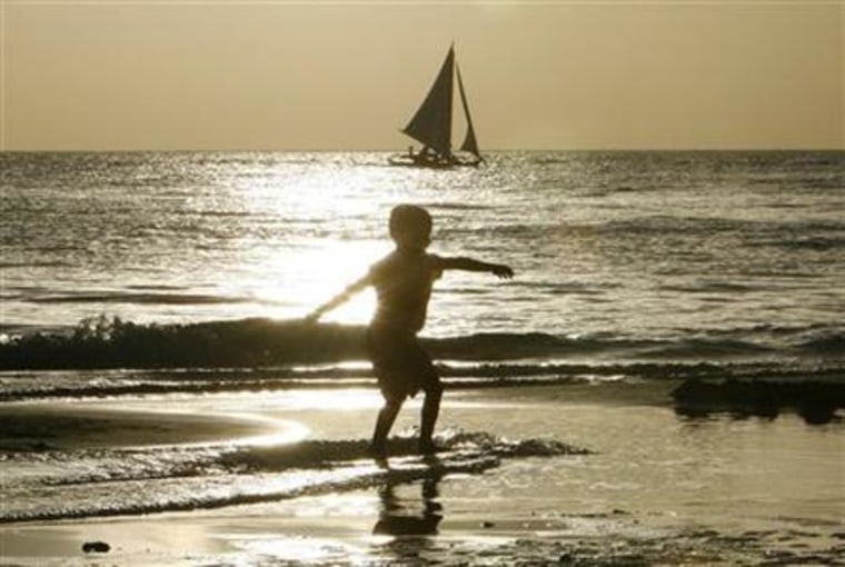 A boy skimboards on the shore on the resort island of Boracay in Malay in the province of Aklan
