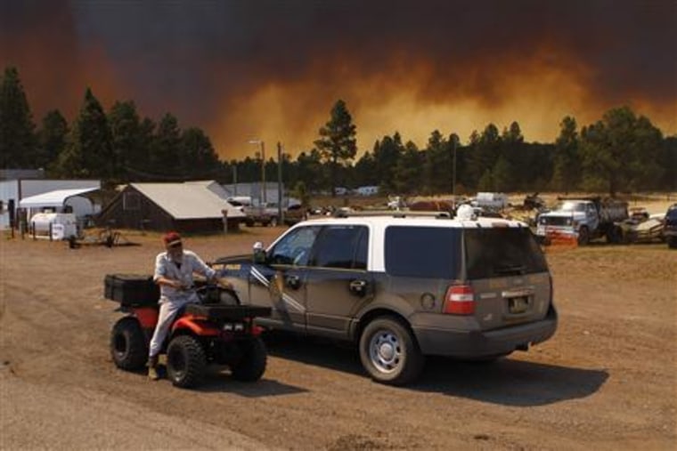 Robert Joseph rides his all terrain vehicles along U.S. Route 180 as smoke from the Wallow Wildfire fills the sky in Luna