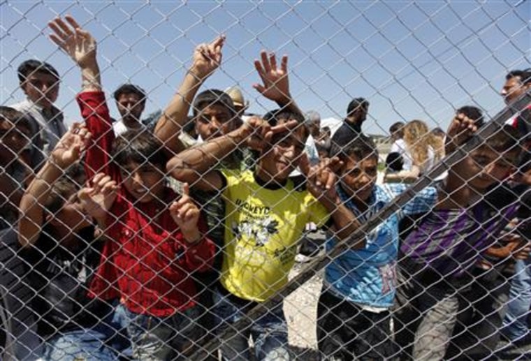 Syrian refugee children stand behind the fence of a refugee camp in the Turkish border town of Boynuegin in Hatay