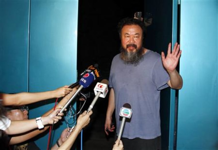 Dissident Chinese artist Ai Weiwei waves from the entrance of his studio after being released on bail in Beijing