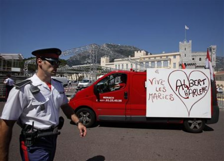 A carabinier of Prince Albert II of Monaco walks past a van with a poster reading \"Albert-Charlene, long live the newly-weds\" in front of Monaco palace