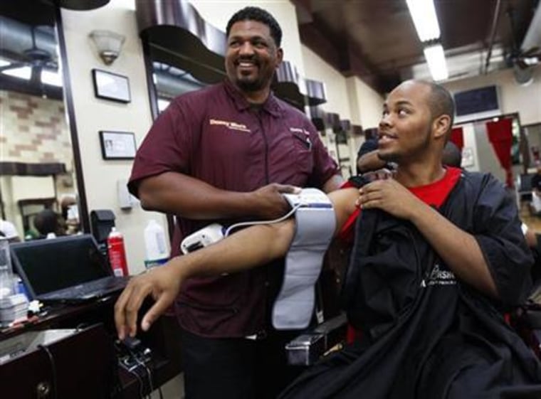 Barber Dennis \"Denny Moe\" Mitchell applies the cuff of an electronic blood pressure machine to Terrell Mack after his haircut at Denny Moe's Superstar Barbershop in New York