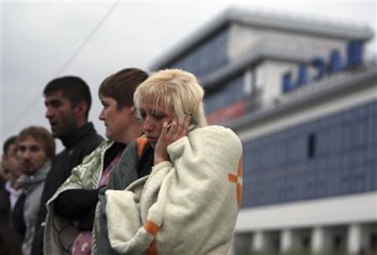 A survivor from the Bulgaria tourist boat, which sank on the Volga river, wraps herself with a blanket while talking on the phone after the arrival at the port of Kazan