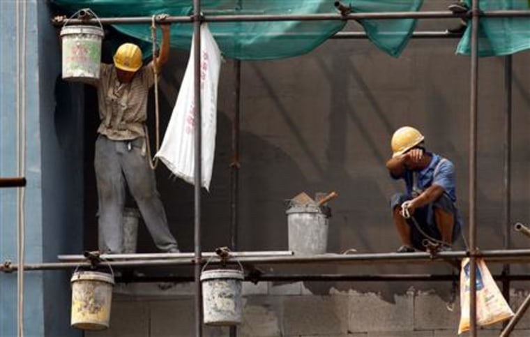 Workers stand atop scaffolding on a residential building construction site in central Beijing