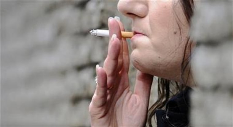 A woman smokes a cigarette outside of an office in central London