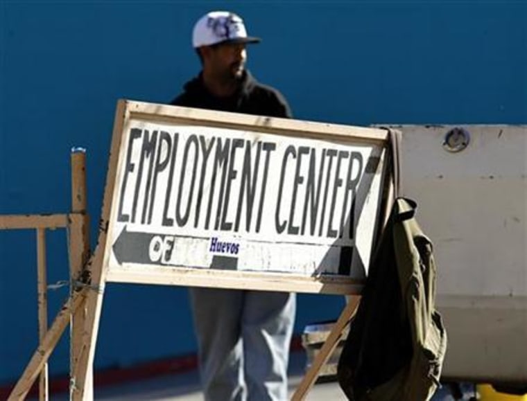 A day laborer stands behind a sign for an employment center in San Diego