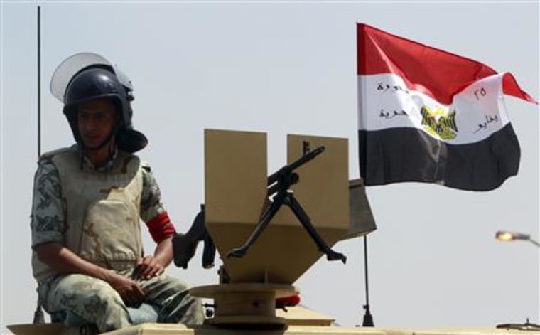 An Egyptian army soldier sits beside an Egyptian flag near the Israeli embassy in Cairo
