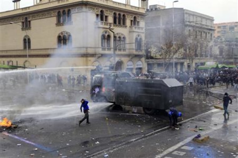 A riot police vehicle releases a jet of water towards demonstrators during a 48-hour national strike at Santiago
