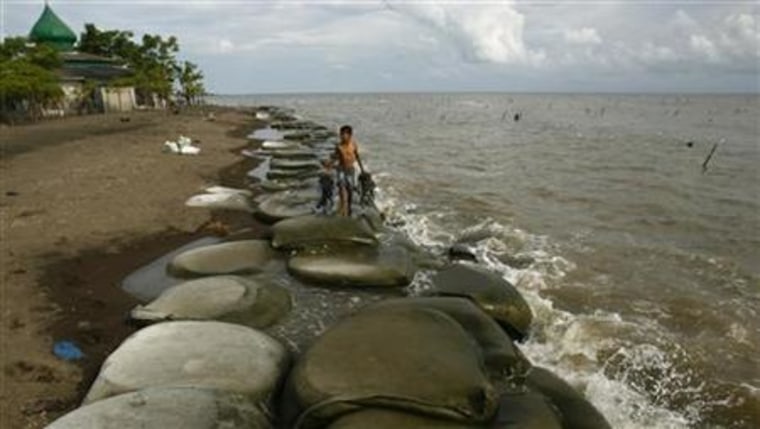 A boy walks on sandbags used to prevent coastal erosion at the Topejawa beach in Takalar district
