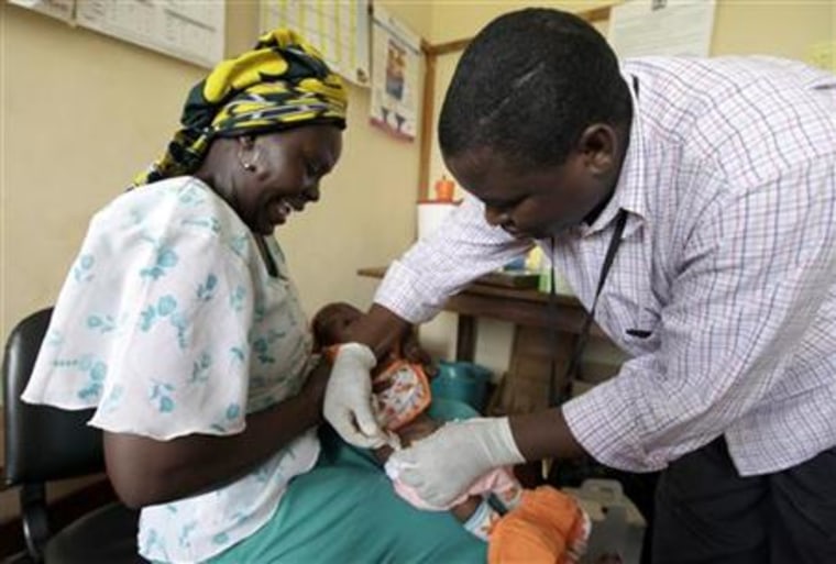 Iren Salama (L) holds her baby Pendo as it is given an injection as part of a malaria vaccine trial at a clinic in the Kenya coastal town of Kilifi
