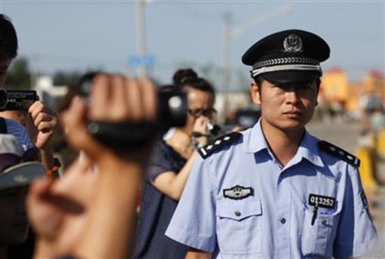 A policeman looks at journalists filming during the verdict hearing of Chinese rights activist Wang Lihong outside a courthouse in Beijing