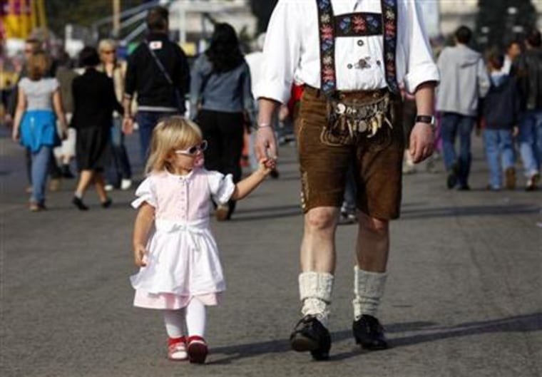 A young festival-goer walks with her father as they visit Oktoberfest in Munich