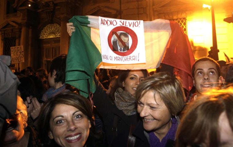 A woman holds up an Italian flag with displaying a picture of outgoing Prime Minister Silvio Berlusconi in front of the Presidential palace in Rome