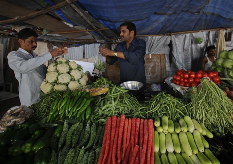 A customer pays after buying vegetables from a street side vendor in Mumbai