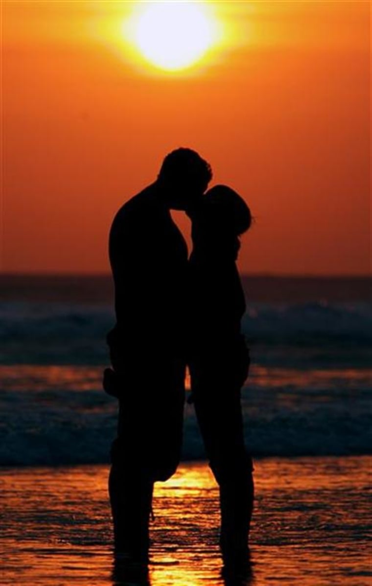 Western tourists kiss during sunset in Bali.
