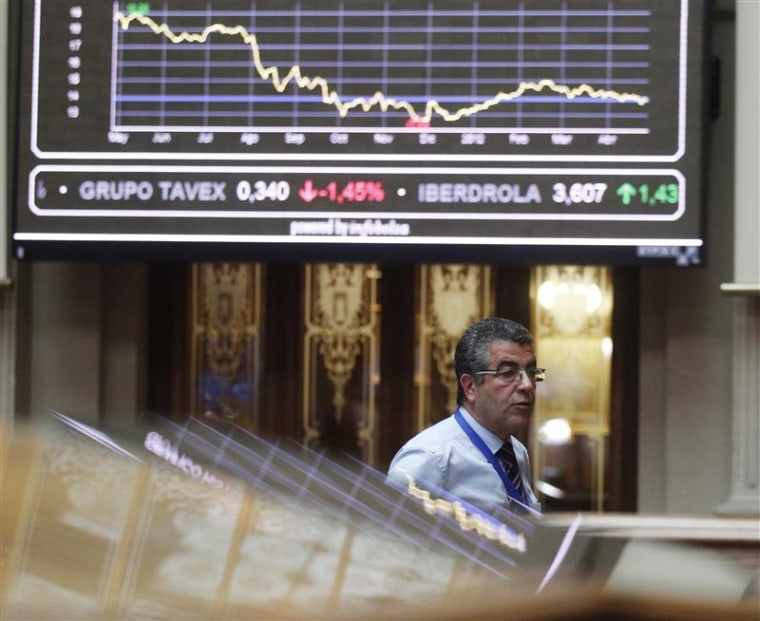 A trader walks under a chart at a bourse in Madrid
