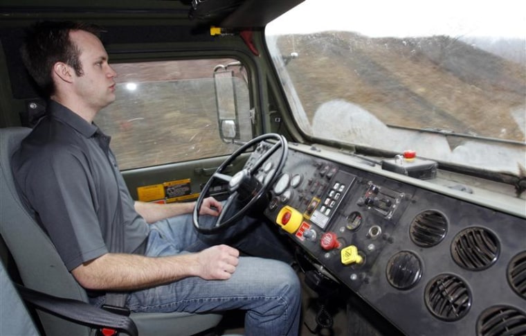 Oshkosh Corporation engineer Noah Zych sits with his hands in his lap while the Terramax autonomous truck drives itself around a test course outside of Pittsburgh, Pennsylvania in this March 1, 2012 file photo