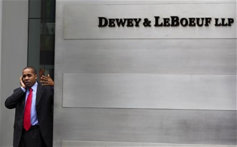A man talks on his phone behind the sign, outside of the building housing the law firm Dewey &amp; LeBoeuf LLP in New York