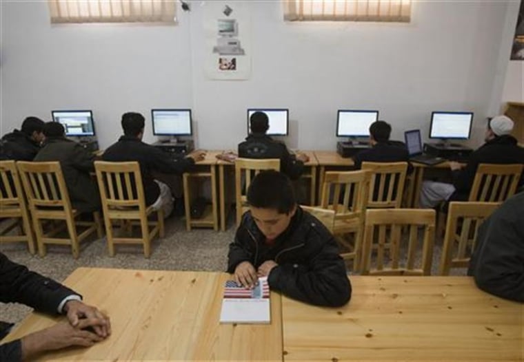 Afghan boy looks at educational book as others use Internet at Lincoln U.S. support library in Herat