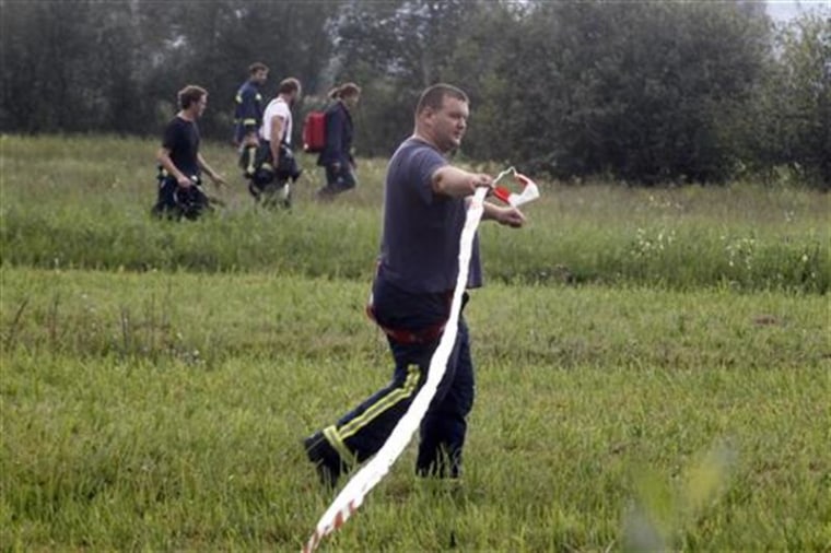 A firefighter places a cordon around an area after it was searched, as rescue personnel try to find the passengers of a hot-air balloon that crashed in Ig near Ljubljana