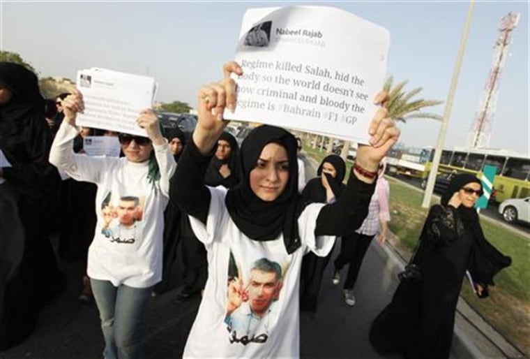 An anti-government protester holds a banner with a tweet by Bahrain human rights activists, Nabeel Rajab's as she participates in a march held to his home to support him, in Budaiya