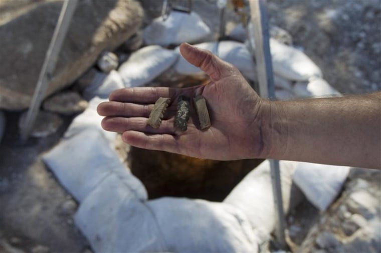 A worker for the Israel Antiquities Authority displays ancient flint sickle blades near a well uncovered in recent excavations in the Jezreel Valley