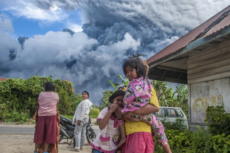 Locals watch as Mount Sinabung spews volcanic ash in North Sumatra, Indonesia, on Monday.