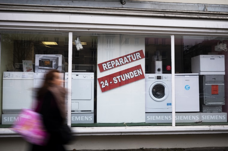 A person walks past a shop offering the repair of electronic equipment and domestic appliances in Berlin on Feb. 26, 2021.