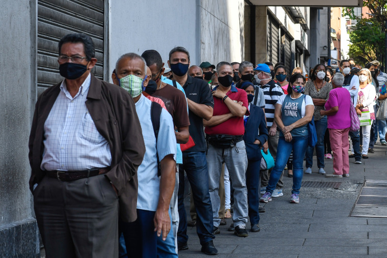 Image: People line up to withdraw cash outside a bank in Caracas on January 28, 2021.