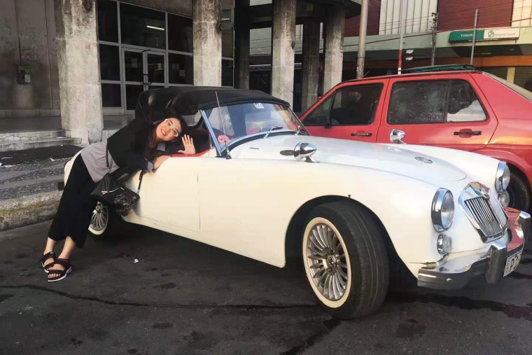 Lulu Yang poses with antique cars on a work trip to Cuba.