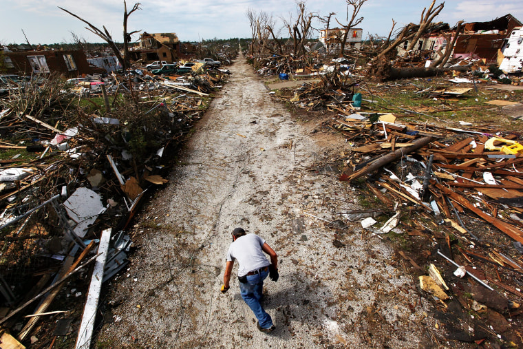 Scott Anderson reaches for a piece of debris near his heavily damaged home after a massive tornado passed through the town killing at least 132 people on May 27, 2011, in Joplin, Mo.