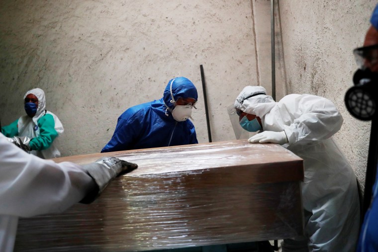 Funeral and crematorium employees work on a coffin carrying the body of a person who died from Covid-19 at San Isidro crematory in Mexico City, Mexico May 21, 2020.