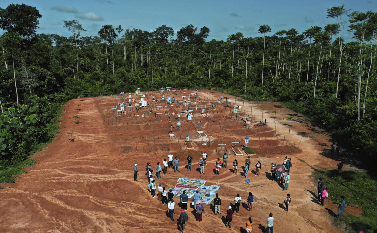 Image: Relatives of people who died from Covid-19 gather next to a clandestine mass grave on the outskirts of Iquitos, Peru, on March 20, 2021