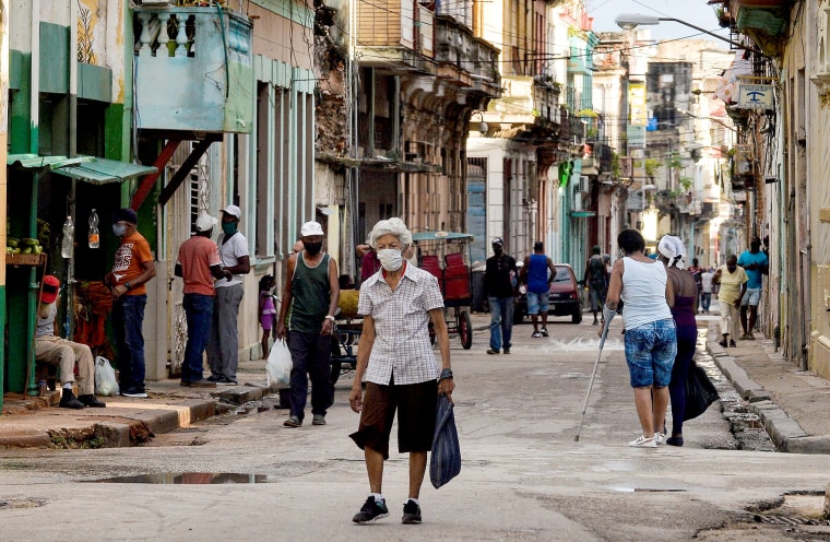 Image:  An elderly person wearing a mask walks along a street of Havana, on April 6, 2021.