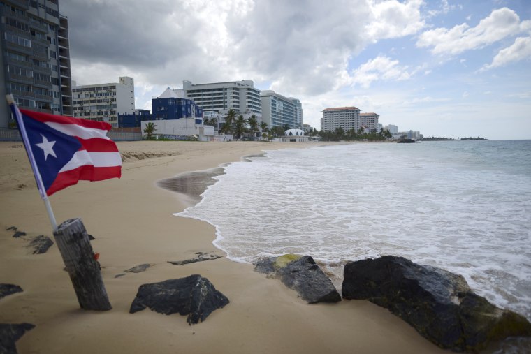 A Puerto Rican flag flies on an empty beach at Ocean Park, in San Juan, Puerto Rico, Thursday, May 21, 2020.